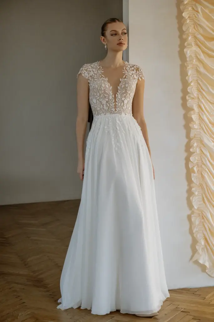 Ein schlichtes Brautkleid aus fließendem Stoff ohne Applikationen fällt in weichen Falten bis zum Boden.