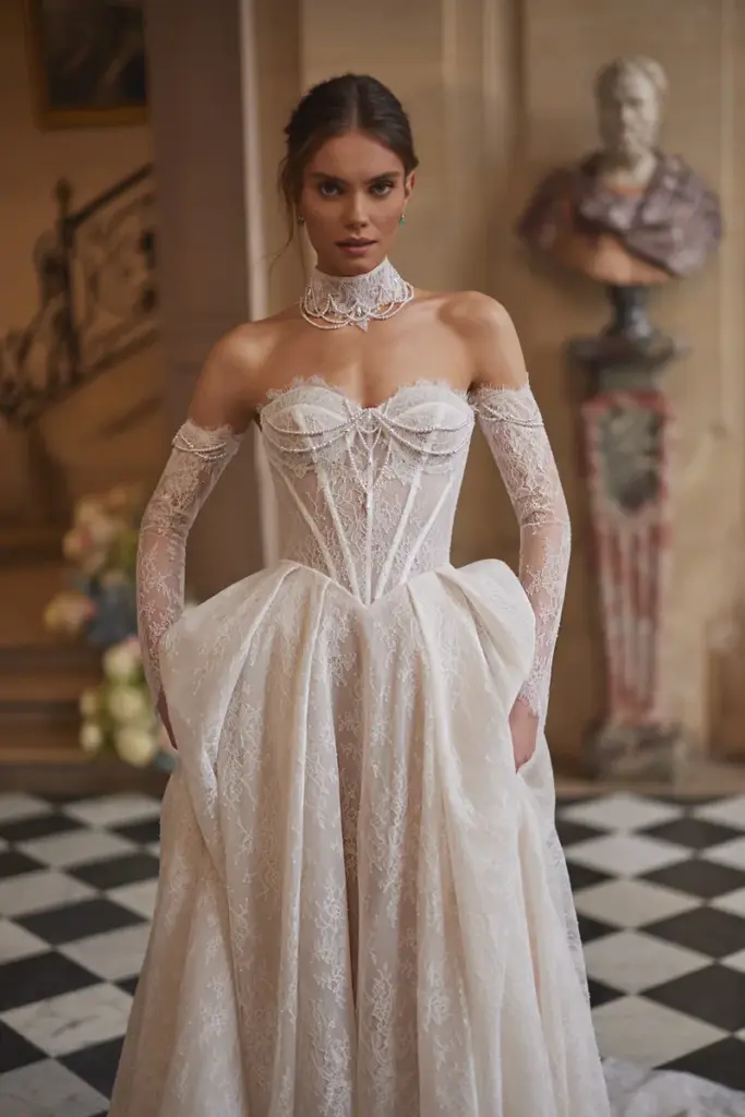 Ein Brautkleid aus durchgehender Spitze mit Korsagen-Oberteil, langen Spitzenärmeln und voluminös gerafftem Rock.