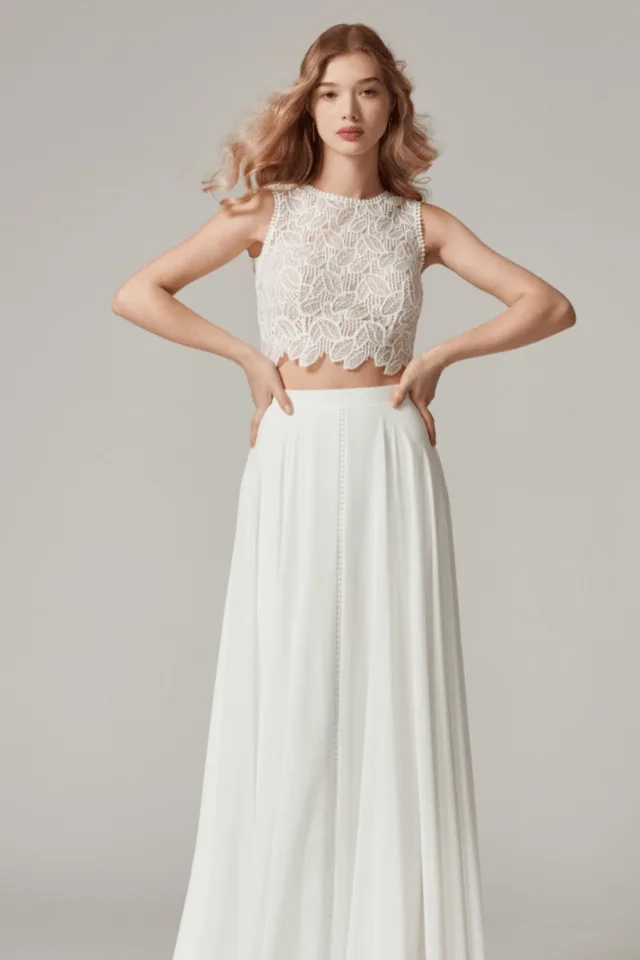 Eine elegante Braut in einem weißen Brautkleid mit spielerischem Spitzentop. Der fließende Rock und die filigranen Details schaffen einen harmonischen Look für besondere Anlässe.
